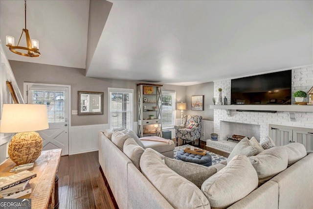 living room with a fireplace, a chandelier, and dark wood-type flooring