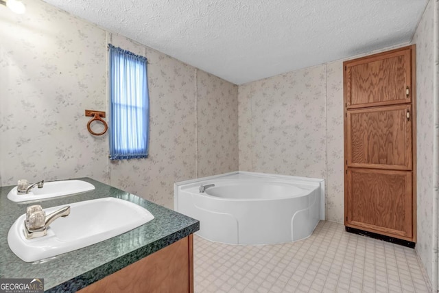 bathroom with vanity, a textured ceiling, and a tub