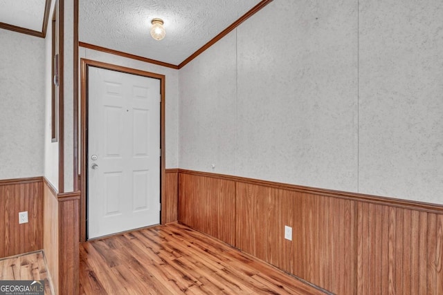 foyer featuring a textured ceiling, light hardwood / wood-style flooring, and crown molding