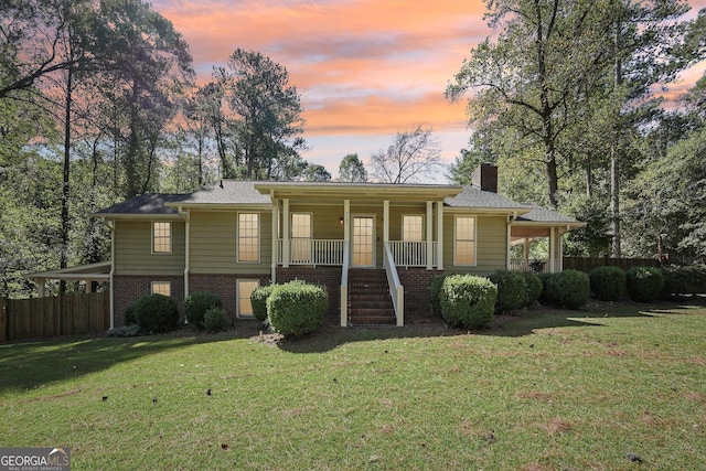 ranch-style house featuring covered porch and a yard