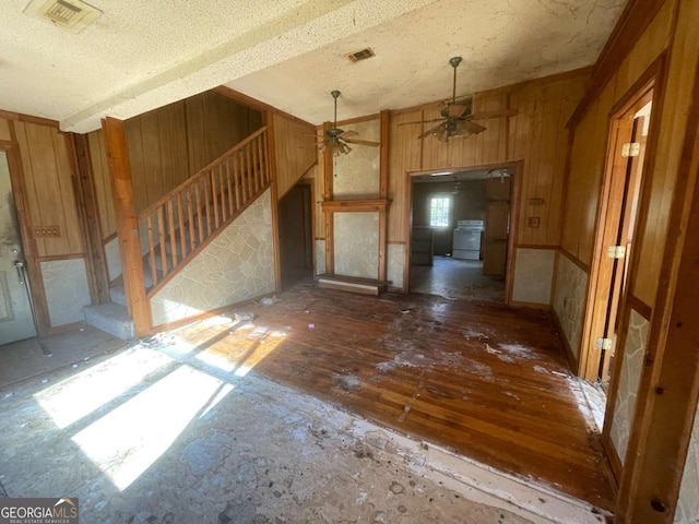 interior space with wooden walls, range, a textured ceiling, and ceiling fan