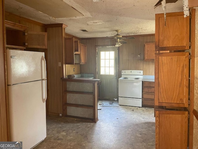 kitchen featuring ceiling fan, wooden walls, a textured ceiling, and white appliances