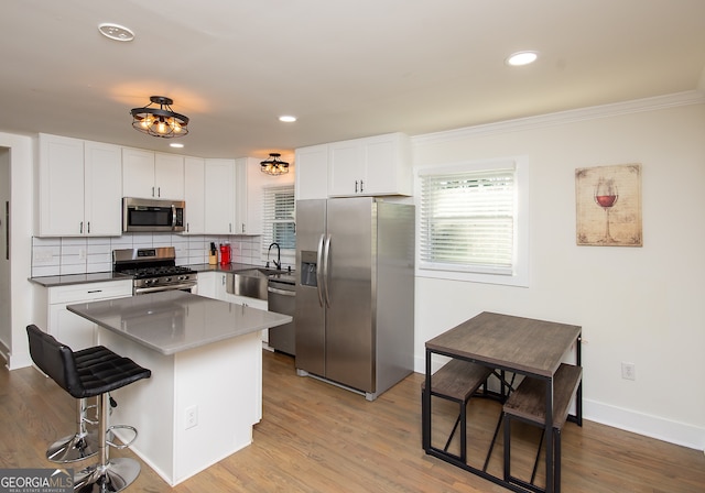 kitchen featuring a center island, appliances with stainless steel finishes, decorative backsplash, white cabinets, and light wood-type flooring