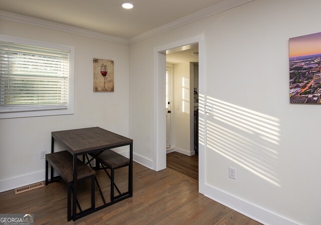 dining space featuring ornamental molding and dark wood-type flooring