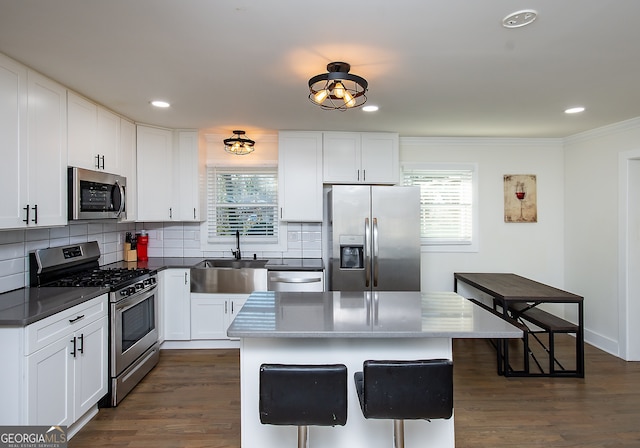 kitchen featuring a kitchen island, white cabinets, a healthy amount of sunlight, and appliances with stainless steel finishes