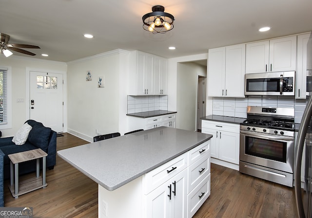 kitchen featuring white cabinetry, a center island, dark hardwood / wood-style floors, backsplash, and appliances with stainless steel finishes