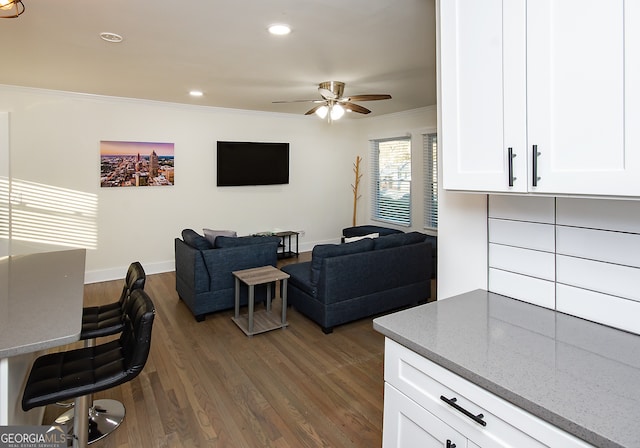 living room featuring crown molding, ceiling fan, and dark wood-type flooring