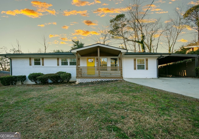 ranch-style house with a lawn, covered porch, and a carport