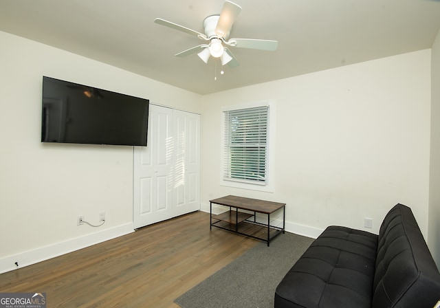 living room with ceiling fan and dark wood-type flooring