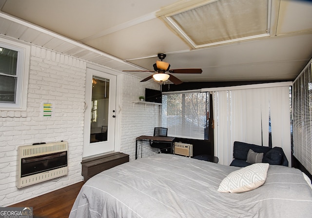 bedroom with ceiling fan, dark hardwood / wood-style floors, brick wall, and heating unit