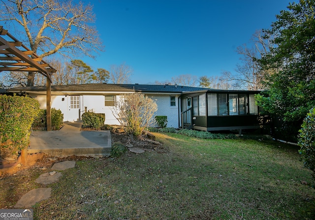 rear view of property featuring a yard, a patio area, a pergola, and a sunroom