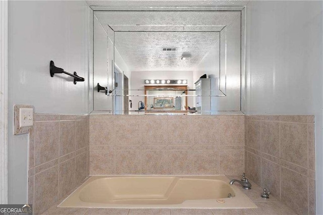 bathroom featuring a textured ceiling and a tub to relax in