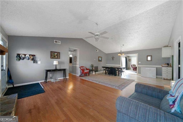 living room with a textured ceiling, light hardwood / wood-style flooring, plenty of natural light, and vaulted ceiling