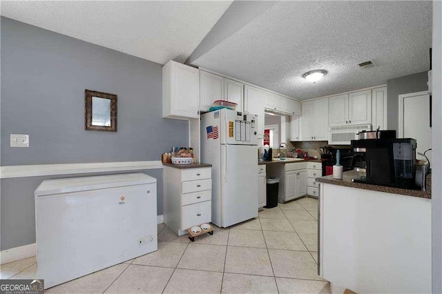 kitchen with white appliances, white cabinets, sink, a textured ceiling, and light tile patterned flooring