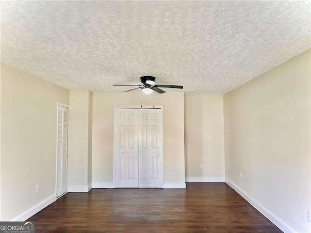 unfurnished bedroom with dark hardwood / wood-style flooring, a textured ceiling, ceiling fan, and multiple closets