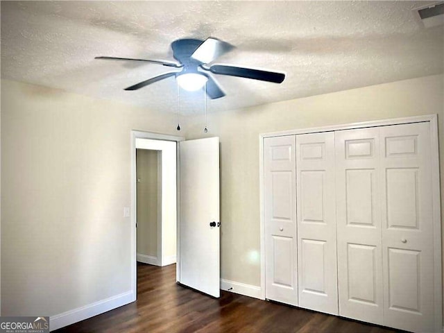 unfurnished bedroom featuring ceiling fan, dark hardwood / wood-style floors, a textured ceiling, and a closet