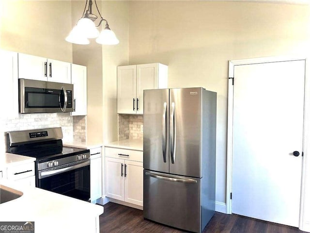 kitchen with pendant lighting, backsplash, stainless steel appliances, and white cabinetry