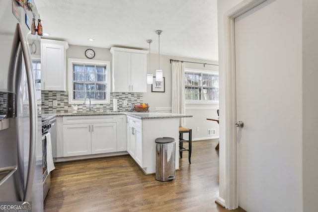 kitchen with kitchen peninsula, white cabinetry, stainless steel refrigerator with ice dispenser, and hanging light fixtures