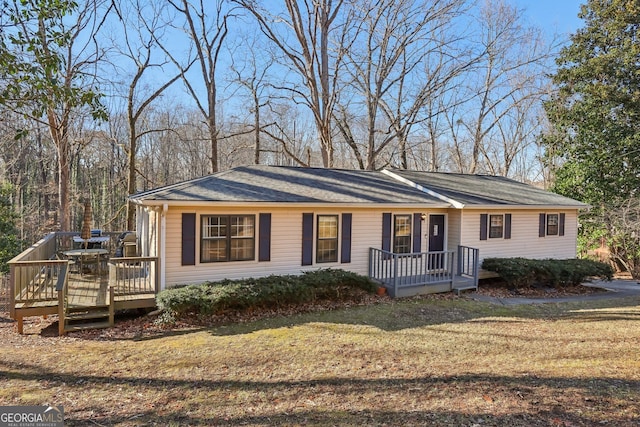 single story home with a wooden deck and a front yard