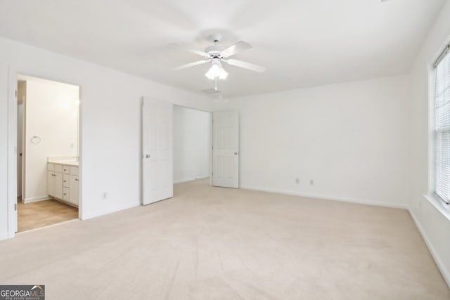 unfurnished bedroom with ceiling fan, light carpet, and connected bathroom