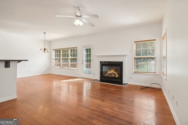 unfurnished living room featuring hardwood / wood-style flooring and ceiling fan with notable chandelier