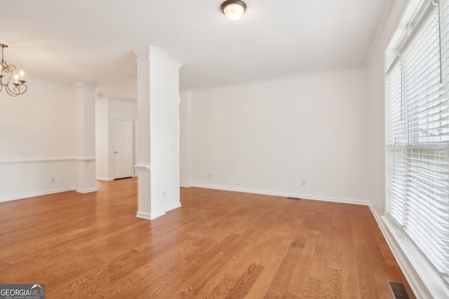 empty room featuring light wood-type flooring and an inviting chandelier