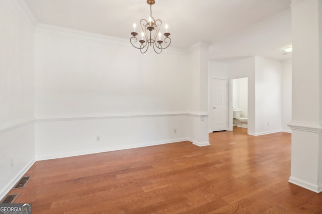 unfurnished room with wood-type flooring, crown molding, and a notable chandelier