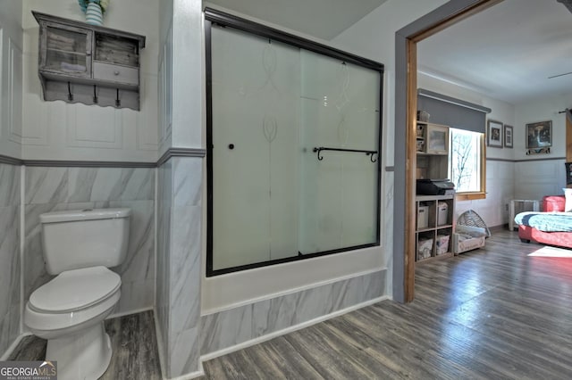 bathroom featuring hardwood / wood-style floors, bath / shower combo with glass door, and toilet