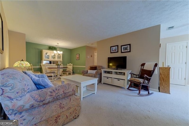 living room featuring a textured ceiling, light carpet, and an inviting chandelier