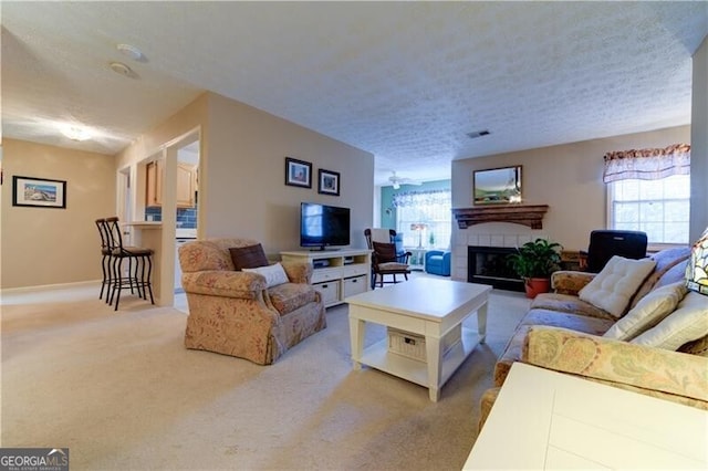 carpeted living room with plenty of natural light, a textured ceiling, and a tile fireplace