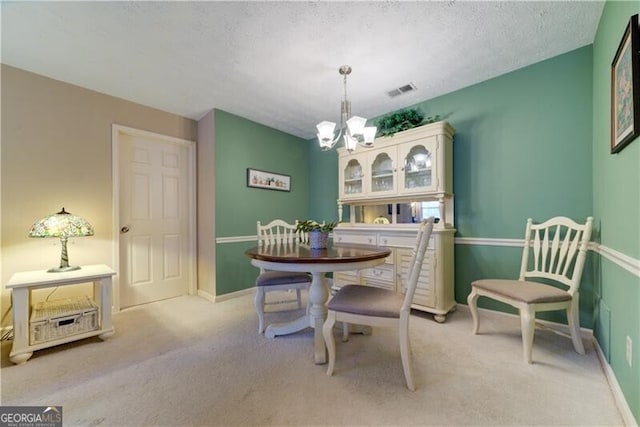 carpeted dining room with a textured ceiling and an inviting chandelier