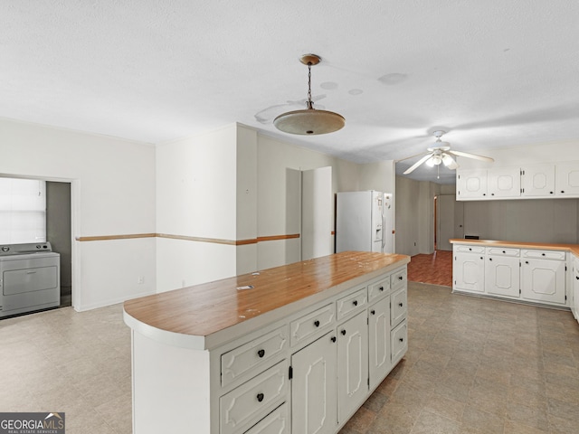 kitchen featuring white cabinetry, hanging light fixtures, a kitchen island, washer / clothes dryer, and white refrigerator with ice dispenser