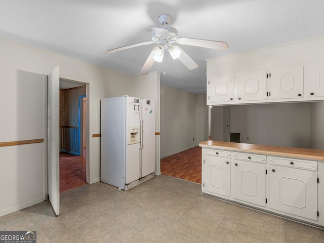 kitchen featuring white cabinetry, ceiling fan, and white refrigerator with ice dispenser