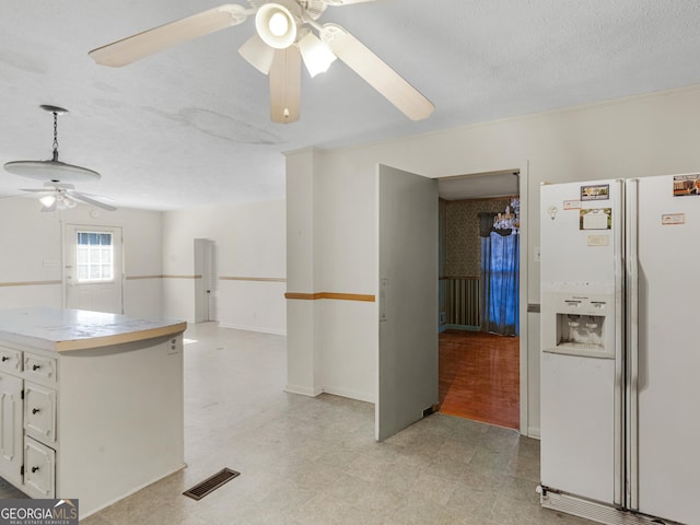 kitchen with decorative light fixtures, a textured ceiling, ceiling fan, white refrigerator with ice dispenser, and white cabinets