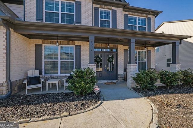 view of exterior entry with a porch and french doors