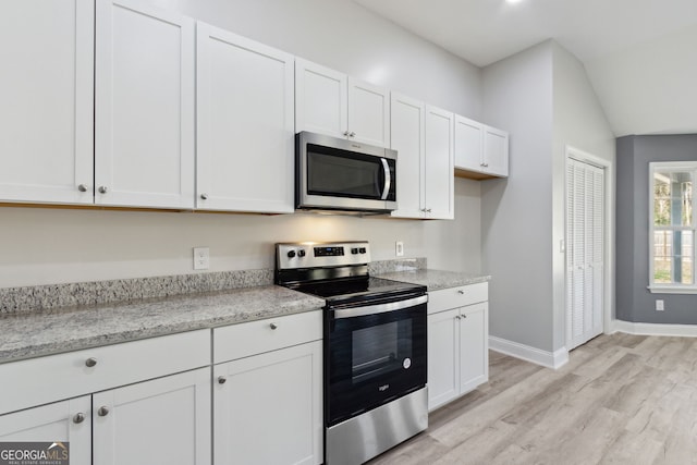 kitchen with white cabinetry, light stone counters, light wood-type flooring, and appliances with stainless steel finishes