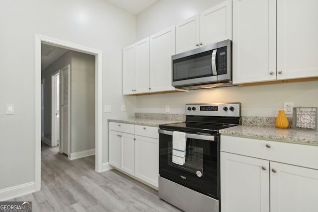 kitchen featuring appliances with stainless steel finishes, white cabinetry, and light stone counters