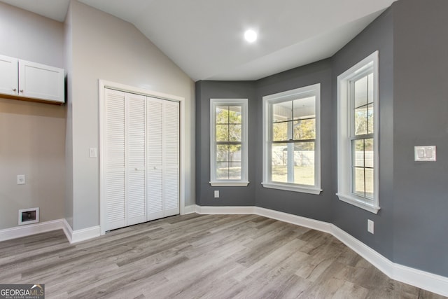 unfurnished bedroom with a closet, light wood-type flooring, and vaulted ceiling