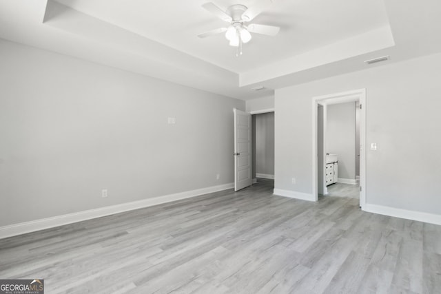 unfurnished bedroom with a raised ceiling, ceiling fan, and light hardwood / wood-style floors