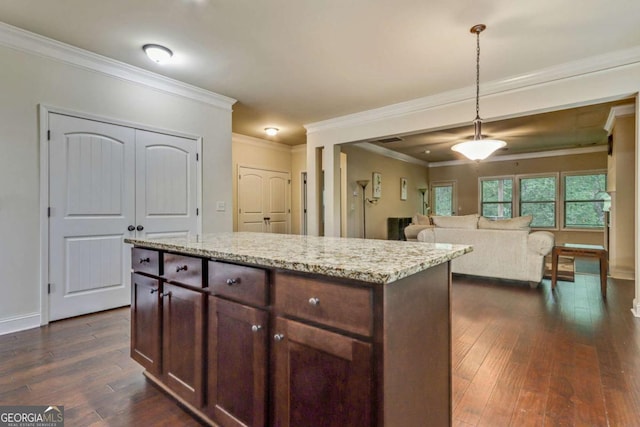 kitchen with light stone countertops, crown molding, dark wood-type flooring, and hanging light fixtures