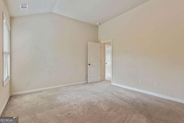 carpeted spare room featuring lofted ceiling