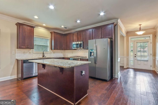 kitchen featuring sink, stainless steel appliances, light stone counters, decorative light fixtures, and a kitchen island