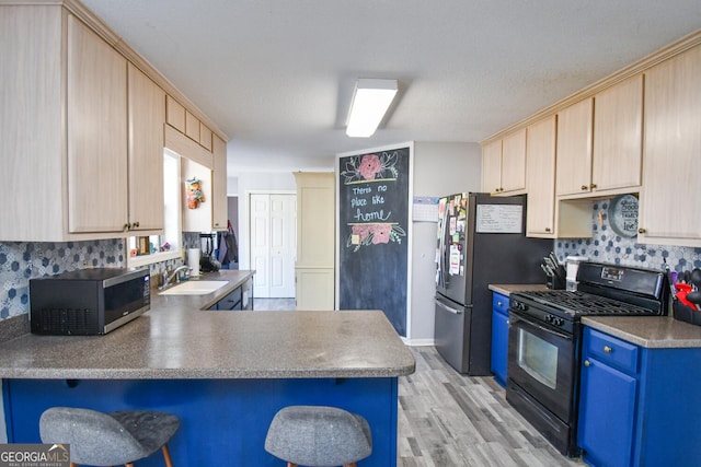 390 Apple Rdg Unit 2, Dawsonville, GA 30534 - kitchen featuring black gas range, a sink, light wood finished floors, blue cabinetry, and a peninsula