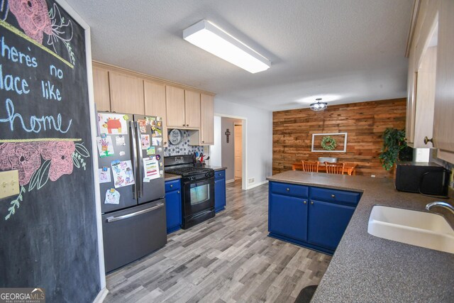 390 Apple Rdg Unit 2, Dawsonville, GA 30534 - kitchen with freestanding refrigerator, black range with gas stovetop, wooden walls, a sink, and blue cabinetry