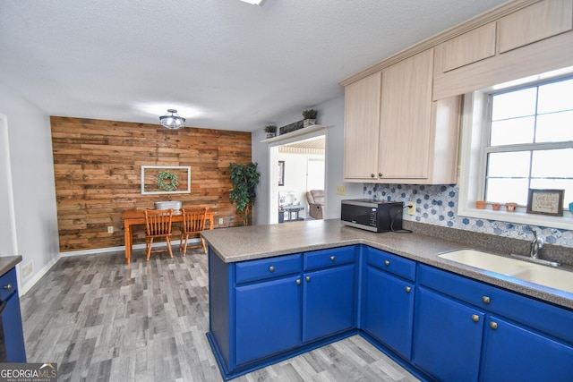 kitchen with wood walls, light brown cabinetry, a wealth of natural light, sink, and blue cabinets