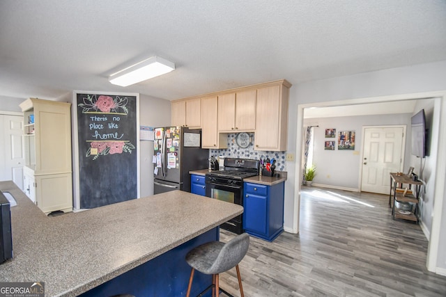 kitchen with a textured ceiling, tasteful backsplash, black gas range oven, stainless steel refrigerator, and light brown cabinets