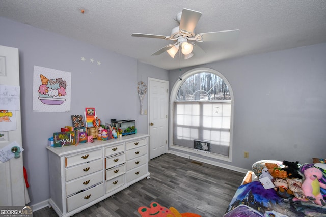 bedroom with ceiling fan, dark hardwood / wood-style floors, and a textured ceiling