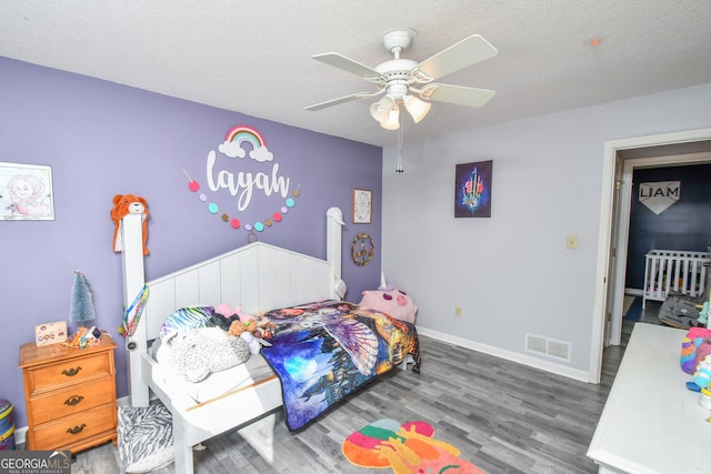 bedroom featuring dark wood-type flooring, a textured ceiling, and ceiling fan