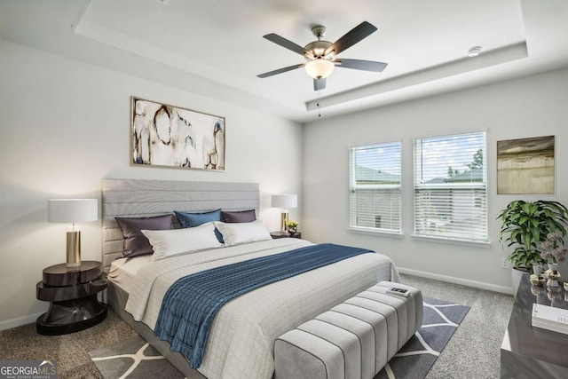 bedroom featuring carpet flooring, a tray ceiling, and ceiling fan