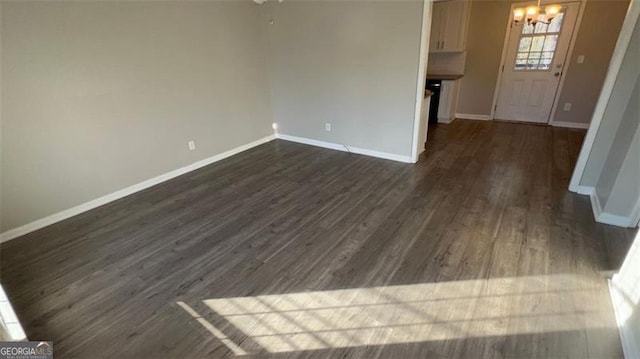 unfurnished living room featuring dark hardwood / wood-style floors and a notable chandelier